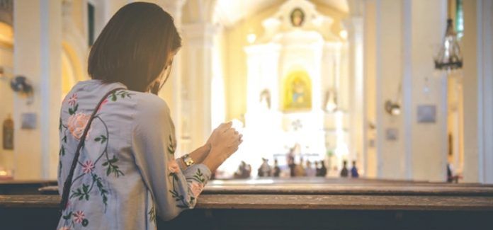 Amar a Deus e ao próximo mulher rezando na igreja